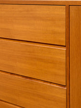 Load image into Gallery viewer, Close-up of a warm medium-brown wooden dresser with three drawers and a matching side panel, showing the wood grain texture.
