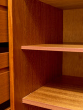 Load image into Gallery viewer, Close-up of a wooden shelving unit with two empty shelves and a drawer front on the left, showing warm medium-brown wood grain.
