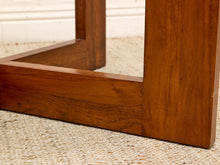 Load image into Gallery viewer, Close-up of a wooden furniture leg and corner joint on a woven beige rug, showing warm medium-brown wood grain.
