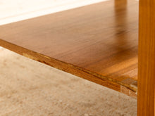Load image into Gallery viewer, Close-up of a warm medium-brown wooden table shelf with visible wood grain and a sliver of the matching wooden frame on the right, set against a light beige carpeted floor.
