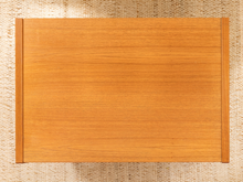 Load image into Gallery viewer, A rectangular wooden board or tray with a warm honey-brown finish and visible wood grain, photographed from above on a woven beige surface.
