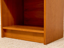 Load image into Gallery viewer, Close-up of a wooden shelf or cabinet corner with a warm medium-brown wood finish, showing the interior shelf space above a light beige carpet.
