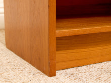 Load image into Gallery viewer, Close-up of a wooden shelf or cabinet corner with warm medium-brown wood grain, standing on a beige woven rug.
