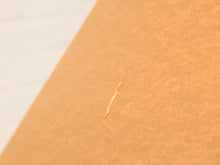 Load image into Gallery viewer, A close-up of a textured brown kraft paper sheet with a small tear or crease, set against a light off-white background.
