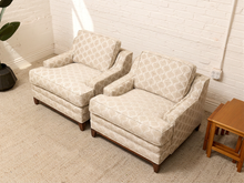 Load image into Gallery viewer, Two matching upholstered armchairs with a beige and white geometric pattern, set against a white brick wall in a room with a light-colored rug and a small wooden side table.
