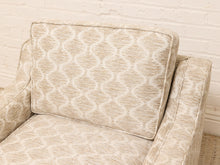 Load image into Gallery viewer, Beige upholstered armchair with a textured geometric trellis pattern, shown against a white brick wall background.
