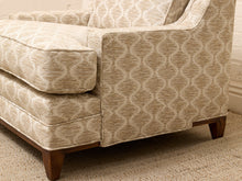 Load image into Gallery viewer, Close-up of an upholstered armchair in a beige and cream geometric patterned fabric with dark wood legs, shown in a real interior setting on a textured rug.
