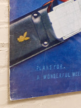 Load image into Gallery viewer, A vintage Playboy magazine cover partially tucked against a light beige brick wall. The cover features the iconic yellow bunny logo on a black leather-like sheath, a white card with a grid pattern, and the text 'PLANS FOR.
