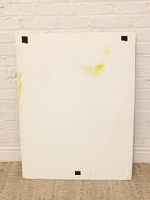 Load image into Gallery viewer, A large, off-white rectangular canvas or board with black tape at the corners, leaning against a white painted brick wall on a woven jute rug.
