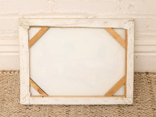 Load image into Gallery viewer, An empty white wooden canvas frame with visible internal wooden supports and tape details, leaning against a white brick wall on a woven jute rug.

