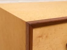 Load image into Gallery viewer, Close-up of a light natural wood cabinet corner with a darker brown wooden trim frame.
