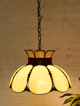 Load image into Gallery viewer, A vintage-style pendant light with a flower-shaped stained glass shade, hanging against a white brick wall.
