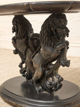 Load image into Gallery viewer, An ornate dark metal table base featuring two sculpted lion figures supporting a round pedestal, photographed close-up against a light neutral background.
