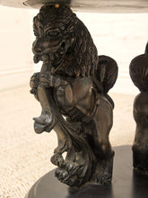 Load image into Gallery viewer, Close-up of a dark carved lion statue support holding up a table, with detailed fur and muscular features, set against a light neutral background.
