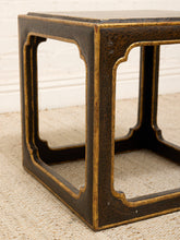 Load image into Gallery viewer, Close-up of a dark brown wooden table leg with gold-toned trim and carved open corner panels, standing on a beige textured rug against a white wall.
