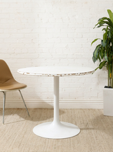 Load image into Gallery viewer, Vintage white round dining table with circular top, single tulip-style pedestal base, and visible wear and chipping along the edge
