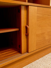 Load image into Gallery viewer, Close-up of a warm medium-brown wooden cabinet with a sliding door and a curved wooden handle, set against a neutral light beige textured floor.
