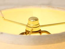 Load image into Gallery viewer, Close-up of a brass lamp shade finial and metal support structure inside a warm yellow illuminated shade.
