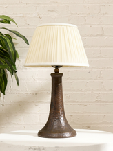 Load image into Gallery viewer, Vintage table lamp with tall sculptural dark brown base and cream pleated fabric shade with matching trim
