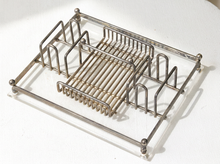 Load image into Gallery viewer, A silver metal dish rack with a slotted center tray, photographed on a white textured fabric background.
