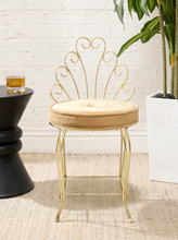 Load image into Gallery viewer, Vintage brass-tone vanity chair with ornate scrolling metal backrest, slender legs, and round button-tufted caramel brown upholstered seat
