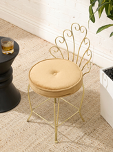 Load image into Gallery viewer, Vintage brass-tone vanity chair with ornate scrolling metal backrest, slender legs, and round button-tufted caramel brown upholstered seat
