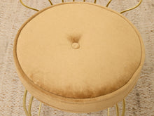 Load image into Gallery viewer, A round tufted stool cushion in a warm beige velvet fabric, mounted on a gold metal wire frame, set on a textured beige rug.
