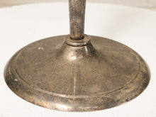 Load image into Gallery viewer, Close-up of a vintage tarnished metal candlestick base with a matching stem, showing a distressed silver and bronze patina on a white textured fabric background.
