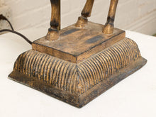 Load image into Gallery viewer, Close-up of the base of a vintage-style table lamp with a distressed bronze finish and ribbed decorative front, standing on a white surface.
