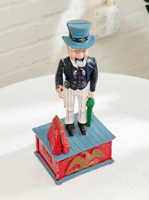 Load image into Gallery viewer, Vintage Uncle Sam figural piggy bank wearing a top hat, dark jacket, bow tie, striped trousers, and standing on a red and blue base
