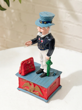 Load image into Gallery viewer, Vintage Uncle Sam figural piggy bank wearing a top hat, dark jacket, bow tie, striped trousers, and standing on a red and blue base
