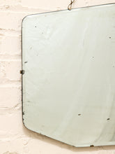 Load image into Gallery viewer, A vintage rectangular wall mirror with a distressed, chipped white enamel finish and a dark metal frame, hanging on a textured white brick wall.
