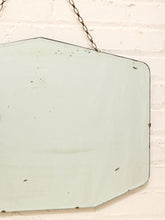 Load image into Gallery viewer, A vintage octagonal mirror with a distressed, weathered finish hangs from a metal chain against a white brick wall.
