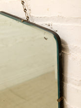 Load image into Gallery viewer, A vintage rectangular wall mirror with a dark metal frame and hanging chain, shown against a white brick wall.
