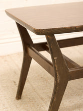 Load image into Gallery viewer, Close-up of a mid-century modern wooden table leg and corner, showing a dark brown distressed finish and a light wood top edge, set on a beige textured rug.
