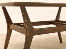 Load image into Gallery viewer, Close-up of a mid-century modern wooden coffee table with a dark brown distressed finish, set against a white brick wall and light beige rug.
