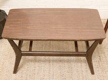 Load image into Gallery viewer, A mid-century modern wooden coffee table with a dark brown wood grain top and angled legs, shown on a woven jute rug.
