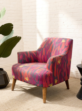 Load image into Gallery viewer, Modern accent chair with red, magenta, purple, pink, and yellow botanical-patterned upholstery, curved arms, and tapered wood legs
