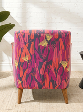 Load image into Gallery viewer, Modern accent chair with red, magenta, purple, pink, and yellow botanical-patterned upholstery, curved arms, and tapered wood legs
