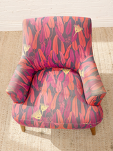 Load image into Gallery viewer, Modern accent chair with red, magenta, purple, pink, and yellow botanical-patterned upholstery, curved arms, and tapered wood legs
