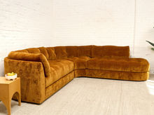 Load image into Gallery viewer, Prima curved sectional sofa in Thriller Amber with golden amber upholstery, deep button-tufted seats, channel-tufted back cushions, and rounded silhouette
