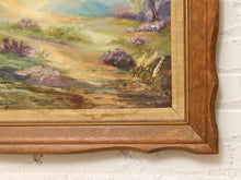 Load image into Gallery viewer, Close-up of a framed landscape painting showing a sunlit grassy field with purple flowers and a tree, set in a warm brown wooden frame against a white brick wall.
