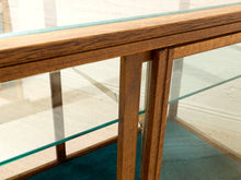 Load image into Gallery viewer, Close-up of a wooden display case or cabinet with glass shelves and doors, showing the wood grain and transparent glass panels.
