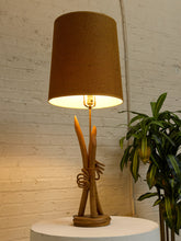 Load image into Gallery viewer, Vintage table lamp with sculptural curved wood base and tall brown woven-texture shade illuminated with a warm glow
