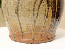 Load image into Gallery viewer, Close-up of a ceramic planter or vase with a speckled beige and brown glaze and dark brown drips, shown on a white surface against a light neutral background.
