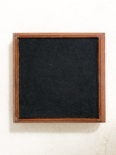 Load image into Gallery viewer, A square black felt or chalkboard-style panel with a medium brown wooden frame, shown against a plain off-white textured background.
