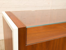 Load image into Gallery viewer, Close-up of a mid-century modern wooden display cabinet with a glass top, featuring a warm brown wood grain finish and a white side trim.
