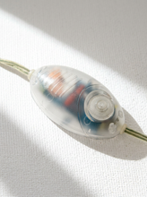 Load image into Gallery viewer, A close-up of a translucent plastic electrical switch or connector with internal components visible, resting on a textured white fabric surface with soft diagonal shadows.
