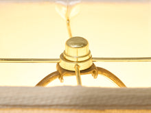 Load image into Gallery viewer, Close-up detail of a brass ceiling fan mount with a ribbed metal cap and thin horizontal support bars, shown against a warm cream background.
