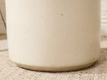 Load image into Gallery viewer, Close-up of a cream-colored ceramic container with a subtle crackle glaze, resting on a woven beige mat.
